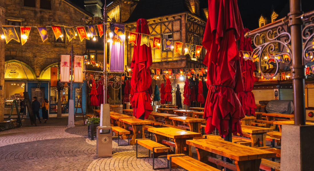 Intérieur d'un café-restaurant de rue festif en plein air, avec des tables et des bancs en bois.